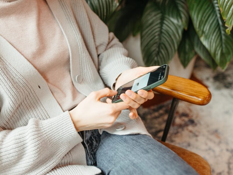 椅子に座ってスマホを操作している